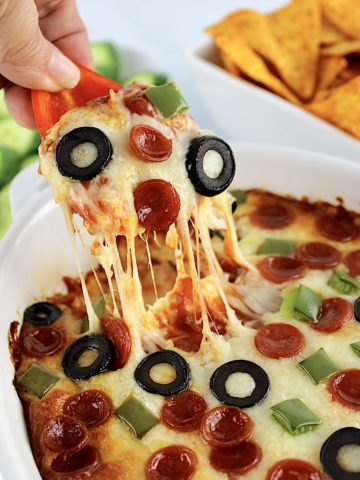 red bell pepper being dipped into Pizza Dip