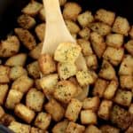 Air Fryer Croutons inn air fryer basket with wooden spoon