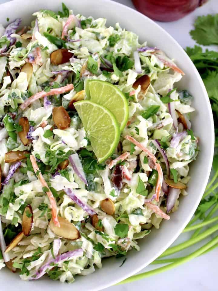 overhead view of Cilantro Lime Coleslaw with 2 lime slices in white bowl