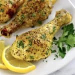 closeup of Lemon Pepper Baked Chicken Drumstick on white plate with lemon slices