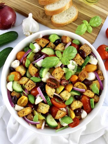 Panzanella Salad in white bowl with sliced bread and veggies in background