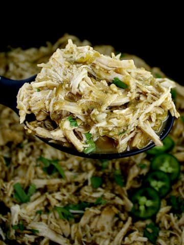 Slow Cooker Salsa Verde Chicken in black serving spoon over slow cooker