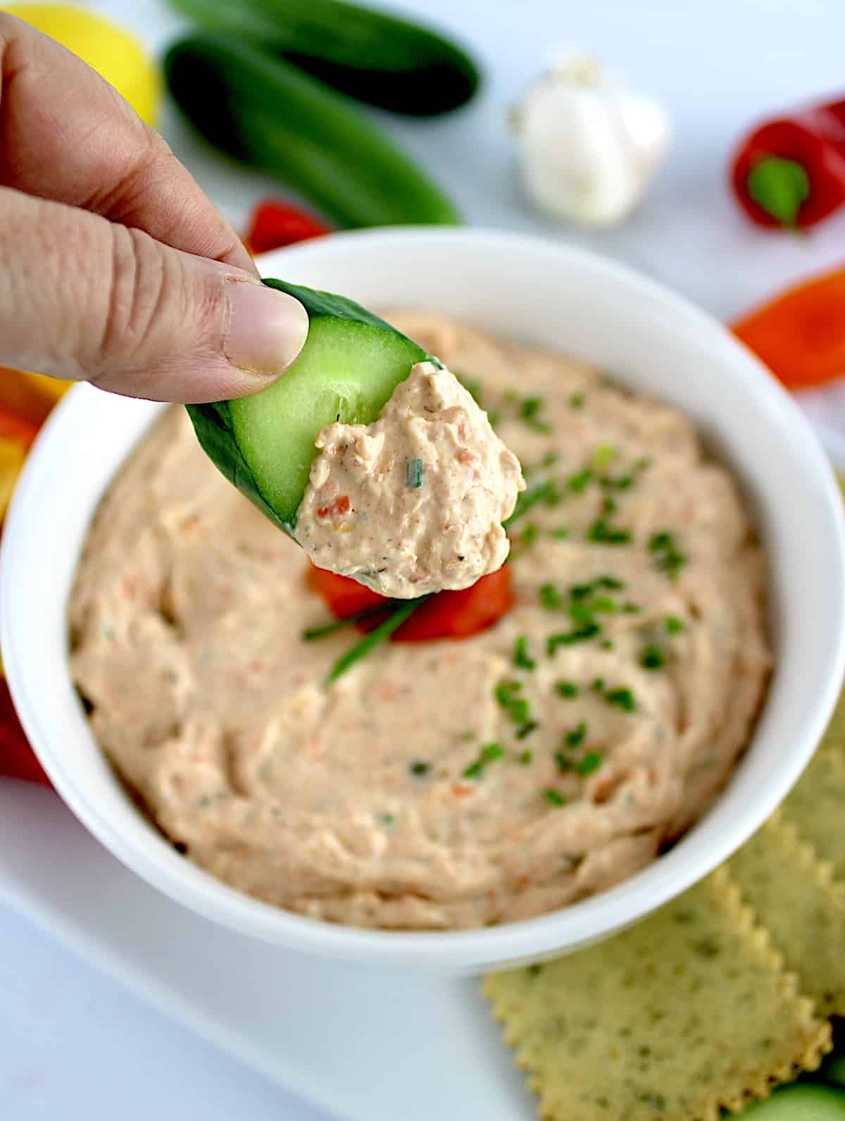 holding up sliced cucumber with Smoked Salmon Dip on it