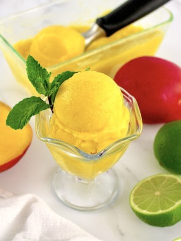 Easy Mango Sorbet in ice cream glass with fruit in background