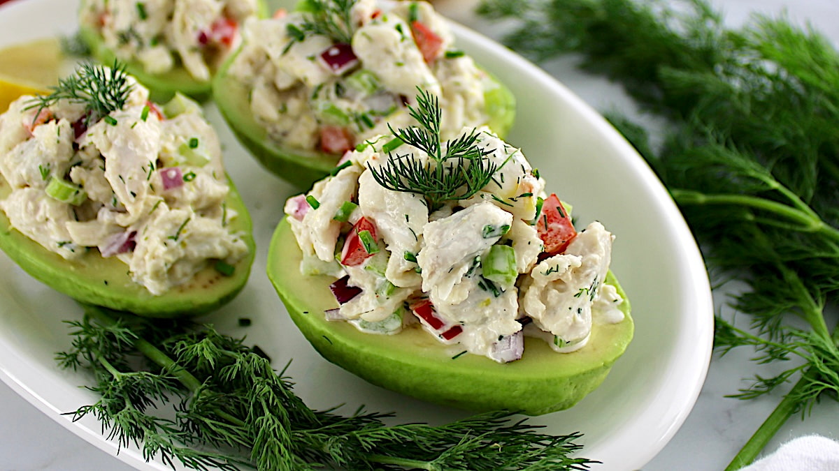 closeup of Crab Salad Stuffed Avocados on white plate with fresh dill