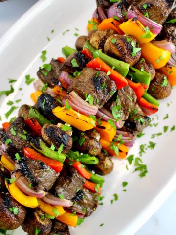 Grilled Beef Kebabs on white plate with chopped parsley