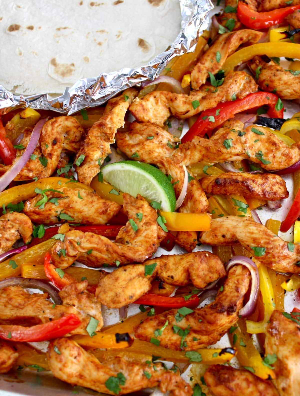Sheet Pan Chicken Fajitas with lime wedge and tortillas in foil