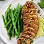 Grilled Steak with Chipotle Lime Butter sliced on white plate with green beans