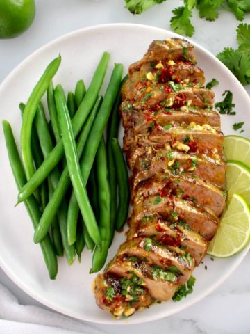 Grilled Steak with Chipotle Lime Butter sliced on white plate with green beans