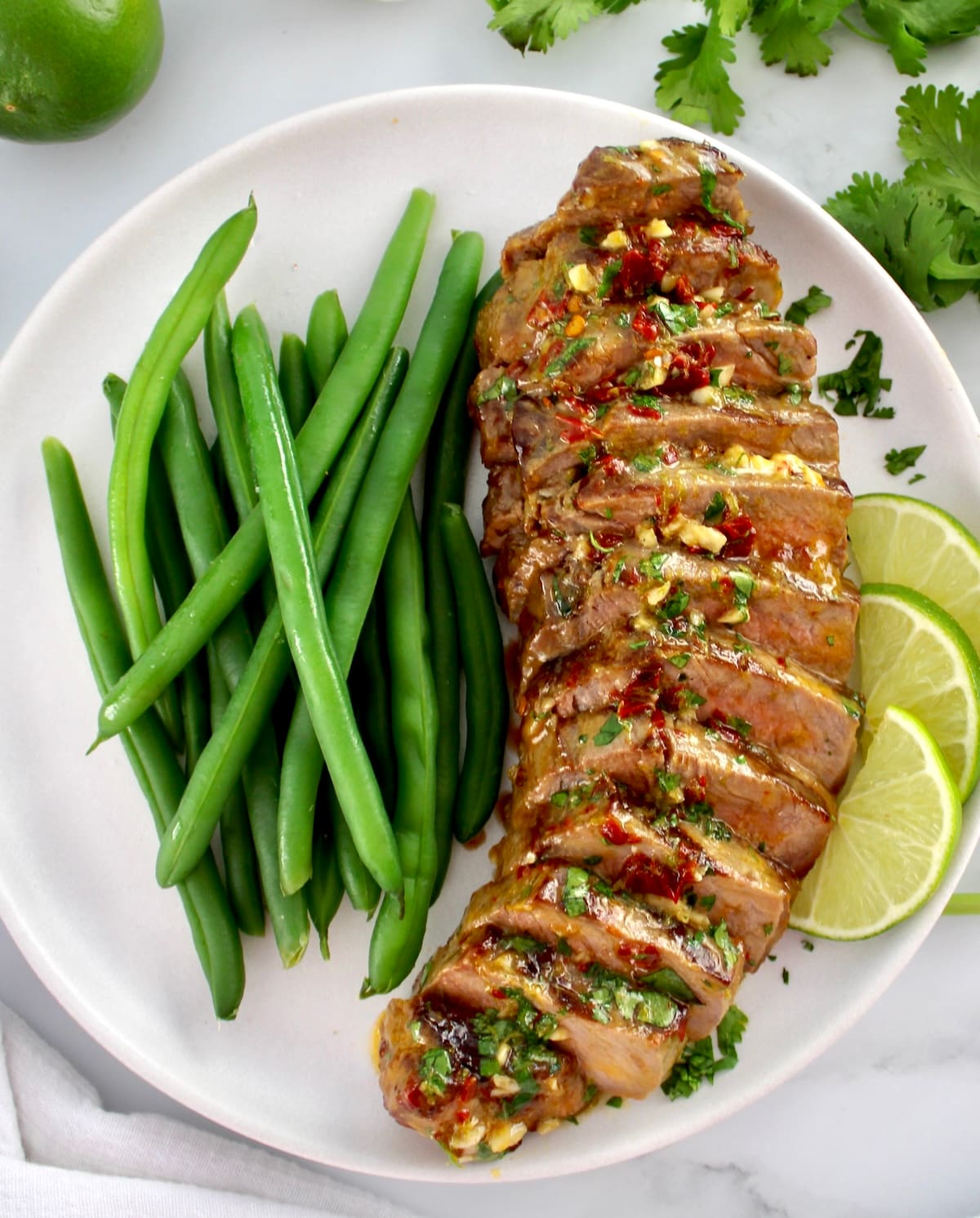 Grilled Steak with Chipotle Lime Butter sliced on white plate with green beans