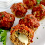 Stuffed Italian Mini Meatloaves on white plate with one cut open and cheese oozing out