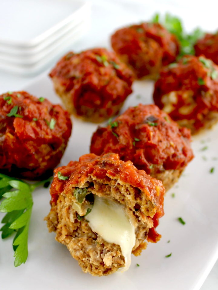 Stuffed Italian Mini Meatloaves on white plate with one cut open and cheese oozing out