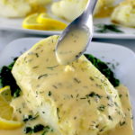 piece of baked cod with lemon beurre blanc being spooned over top