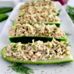 Dill Pickle Tuna Cucumber Boats lined up on white plate with fresh dill
