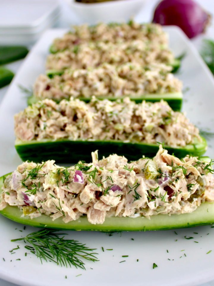 Dill Pickle Tuna Cucumber Boats lined up on white plate with fresh dill