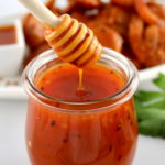 Hot Honey Sauce in glass jar with honey dipper dripping