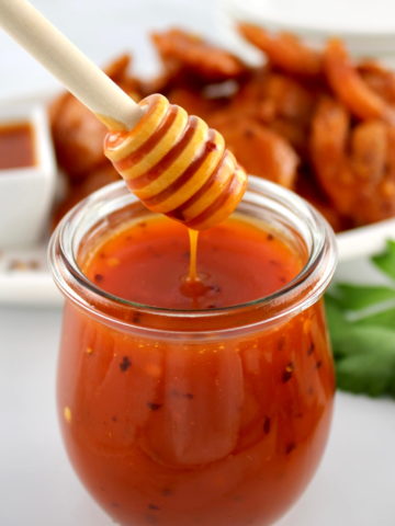 Hot Honey Sauce in glass jar with honey dipper dripping