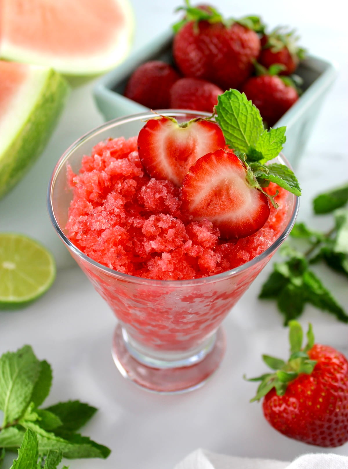 Strawberry Watermelon Granita in glass with strawberries, lime and mint in back