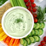 overhead view of Whipped Cottage Cheese Dip in white bowl with fresh veggies and crackers around
