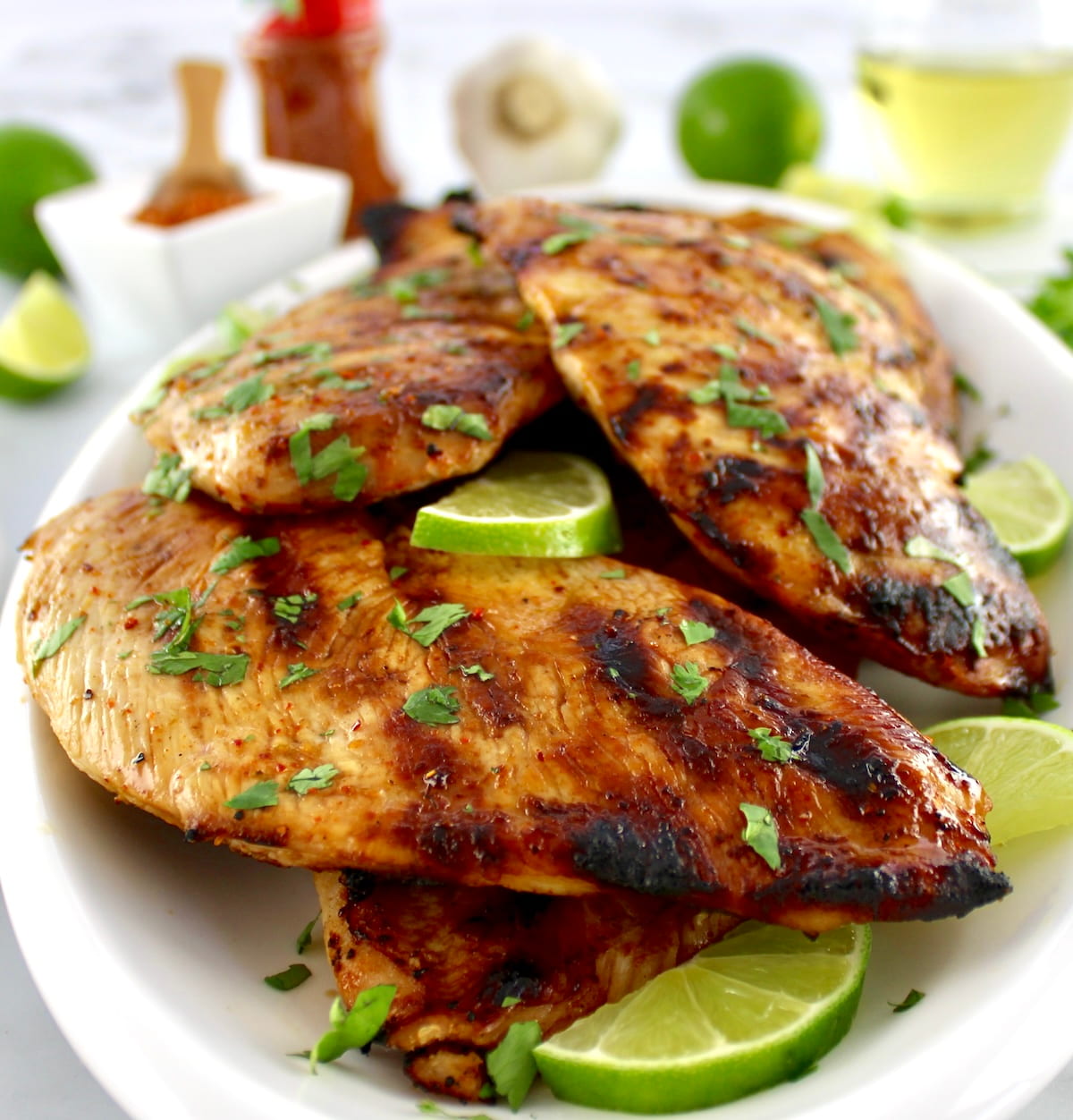 Grilled Tajin Chicken on white plate with lime and cilantro