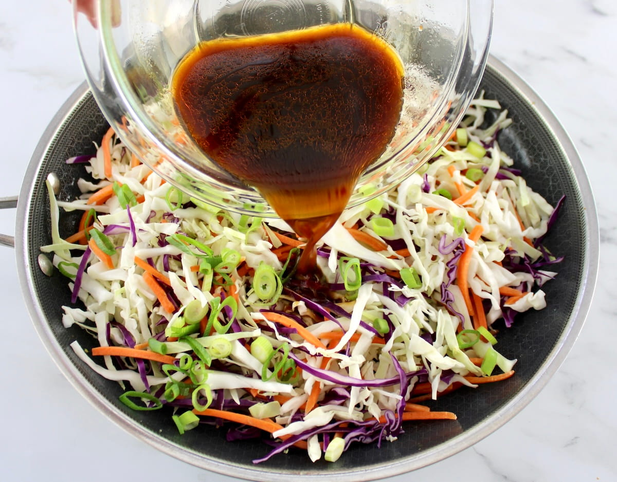 Shrimp Egg Roll in a Bowl sauce being poured over coleslaw mix in skillet