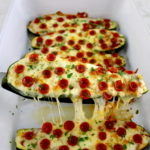 Zucchini Pizza Boat being lifted out of white casserole