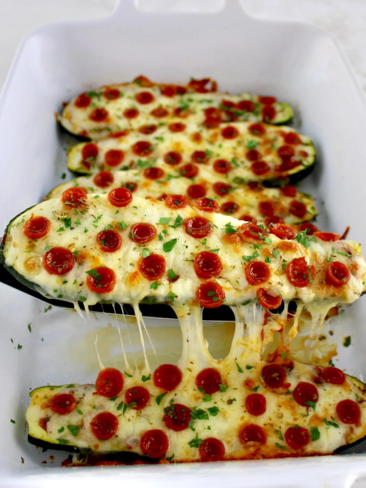 Zucchini Pizza Boat being lifted out of white casserole