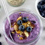 Blueberry Overnight Oats in glass jar with spoon and blueberries with almonds on top