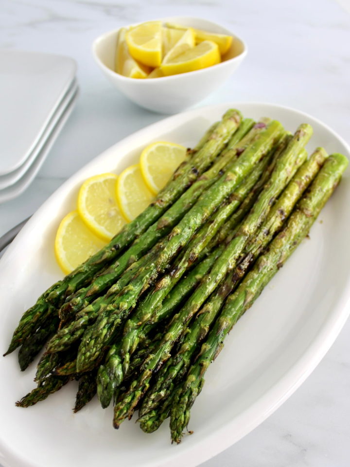 Easy Grilled Asparagus on white oval plate with lemon slices
