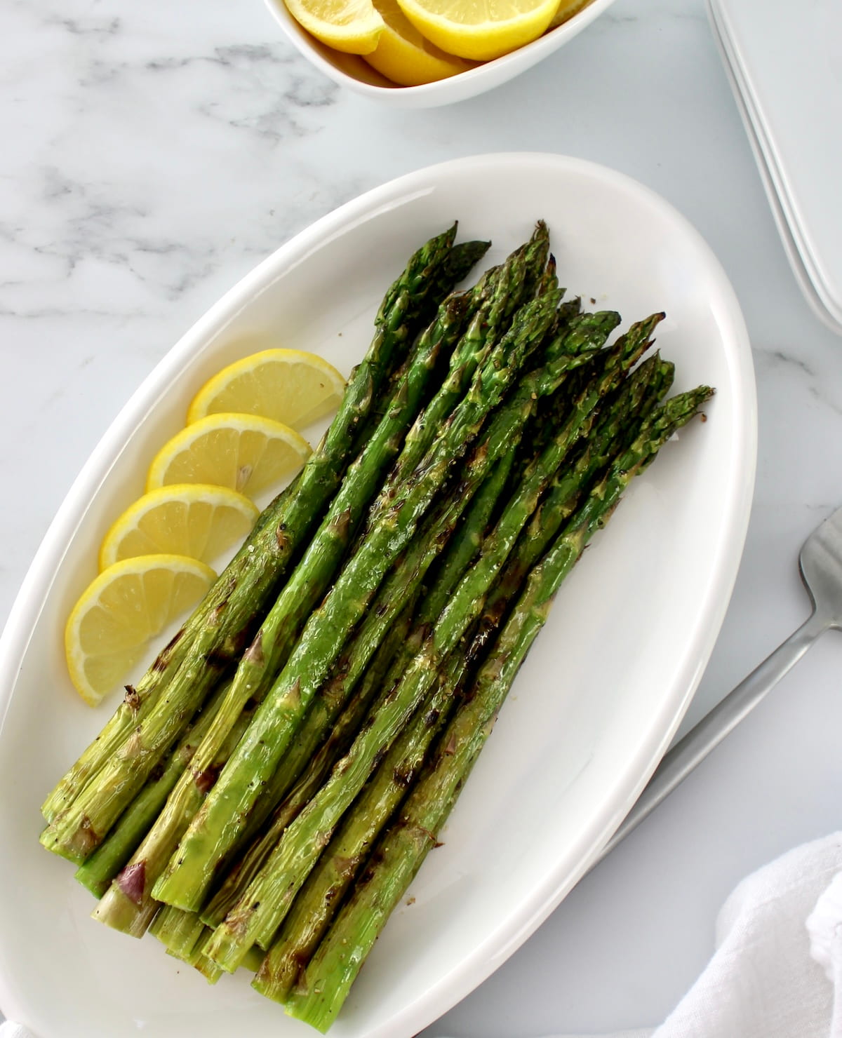 Easy Grilled Asparagus on white plate with lemon slices