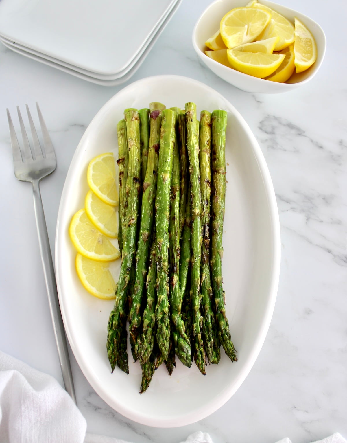 overhead view of Easy Grilled Asparagus on white plate with lemons
