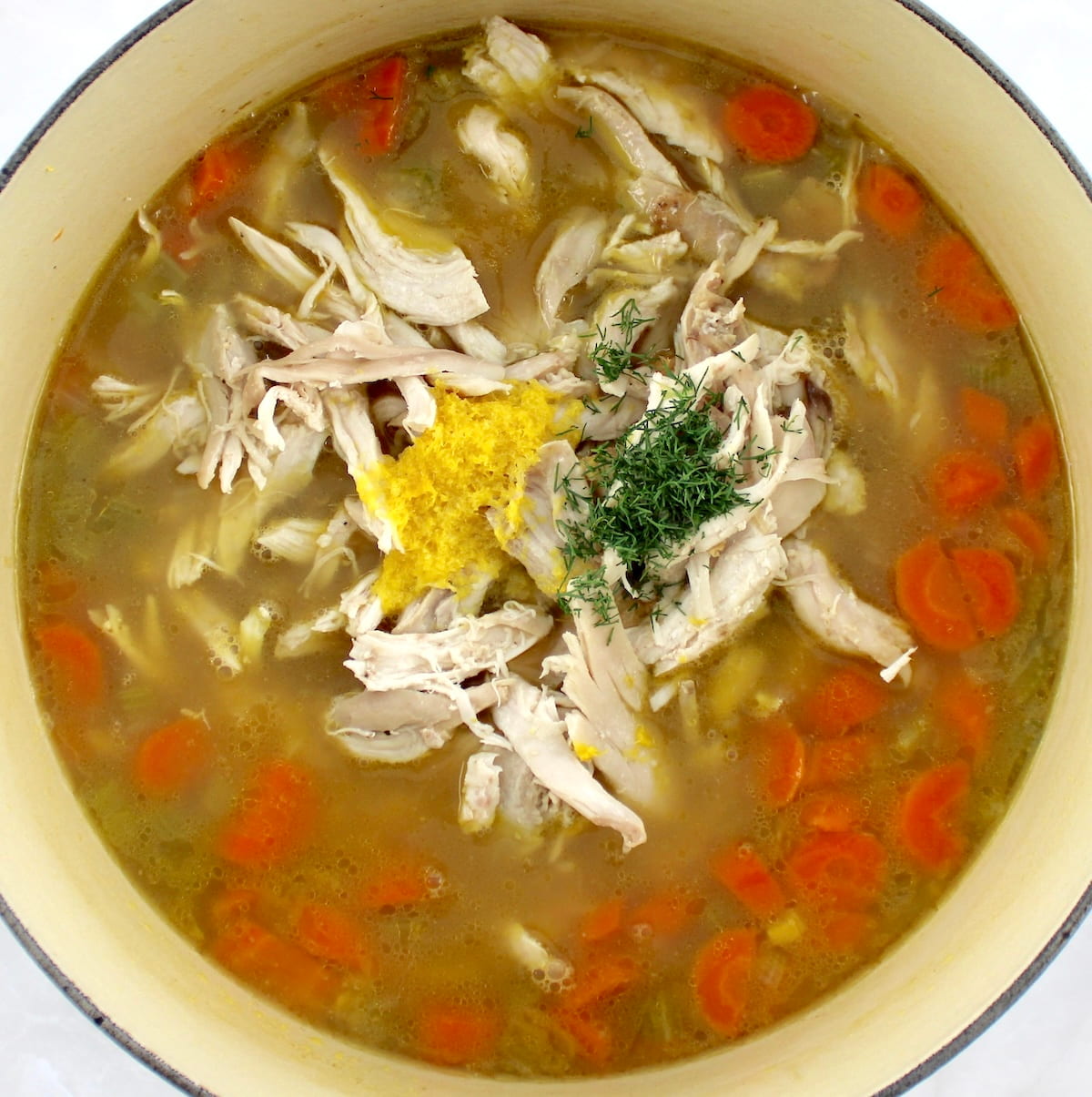 Lemon Orzo Chicken Soup in dutch oven with chicken, lemon zest and dill on top