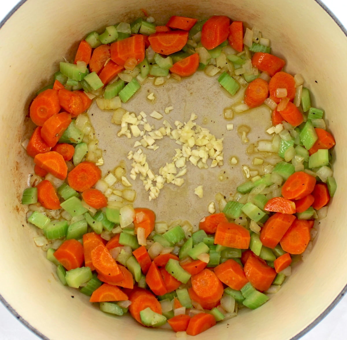 cooked chopped carrots, celery and onions with garlic in center of dutch oven