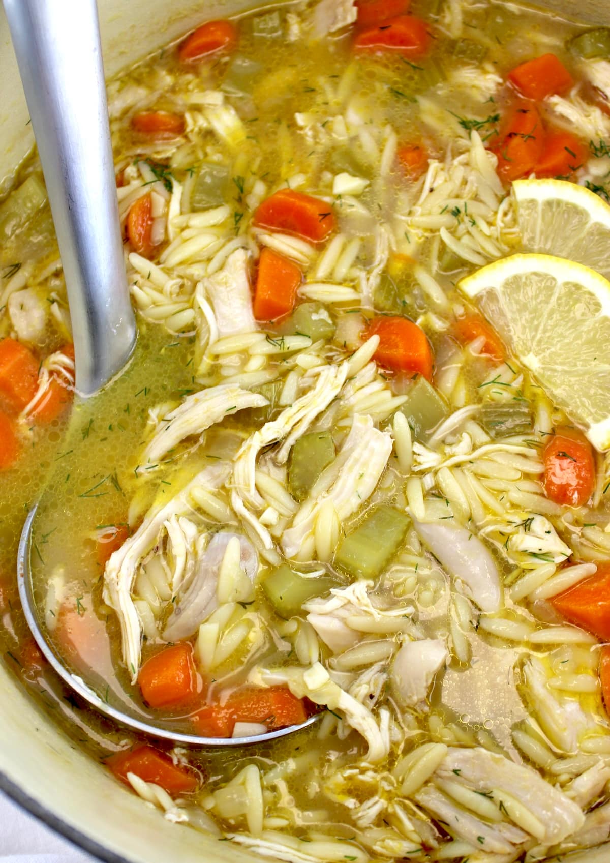 closeup of Lemon Orzo Chicken Soup with silver ladle