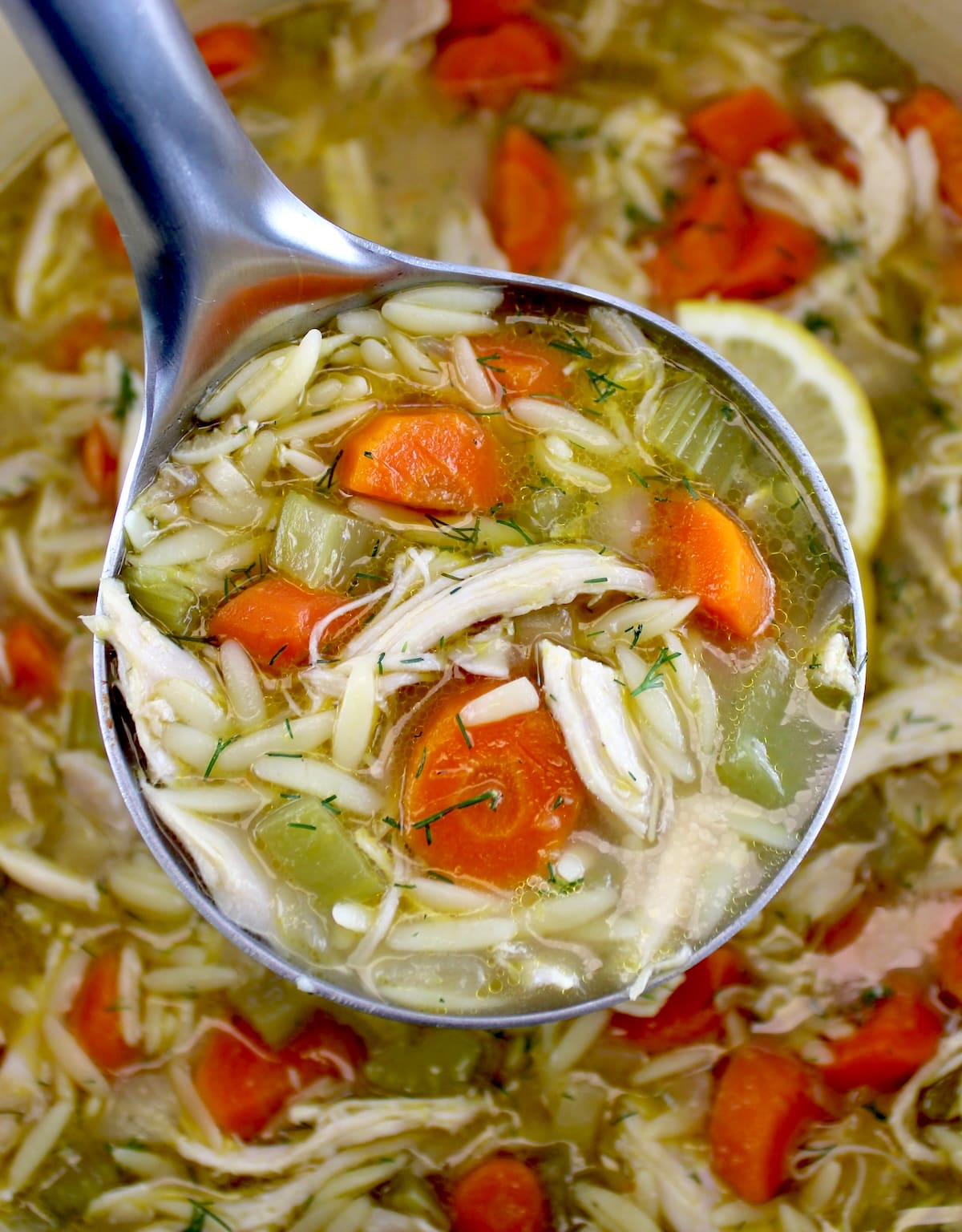 closeup of Lemon Orzo Chicken Soup in silver ladle