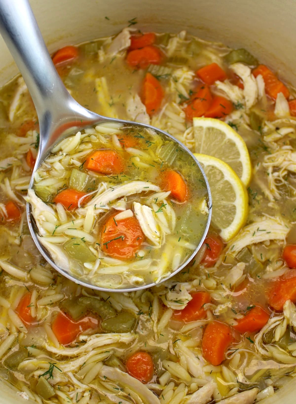 closeup of Lemon Orzo Chicken Soup in silver ladle