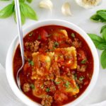 Ravioli Soup in white in white bowl with silver spoon on side
