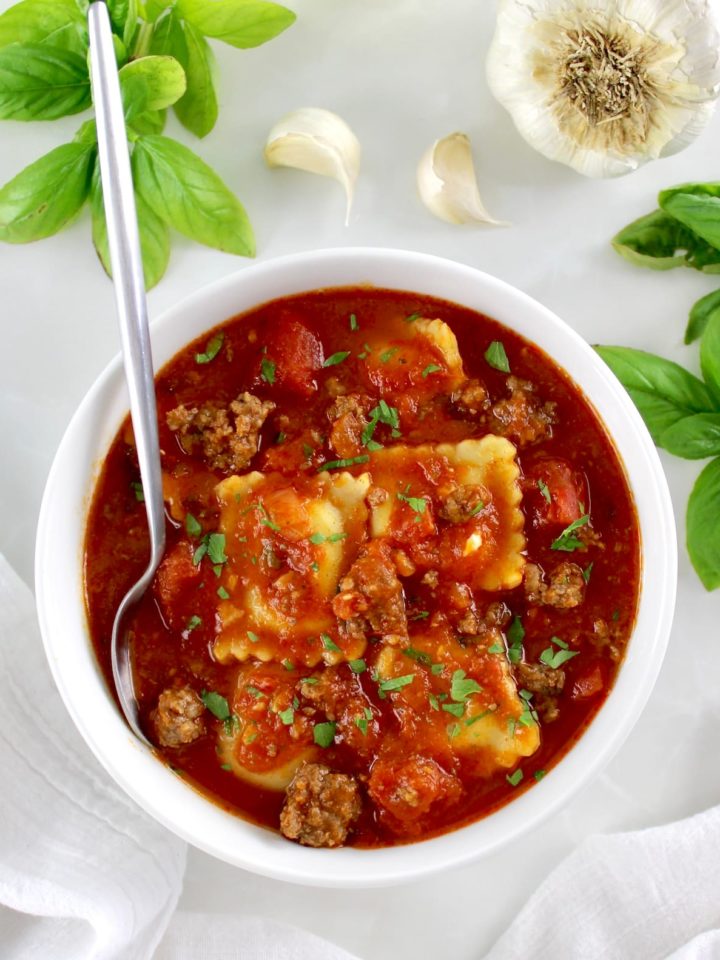 Ravioli Soup in white in white bowl with silver spoon on side