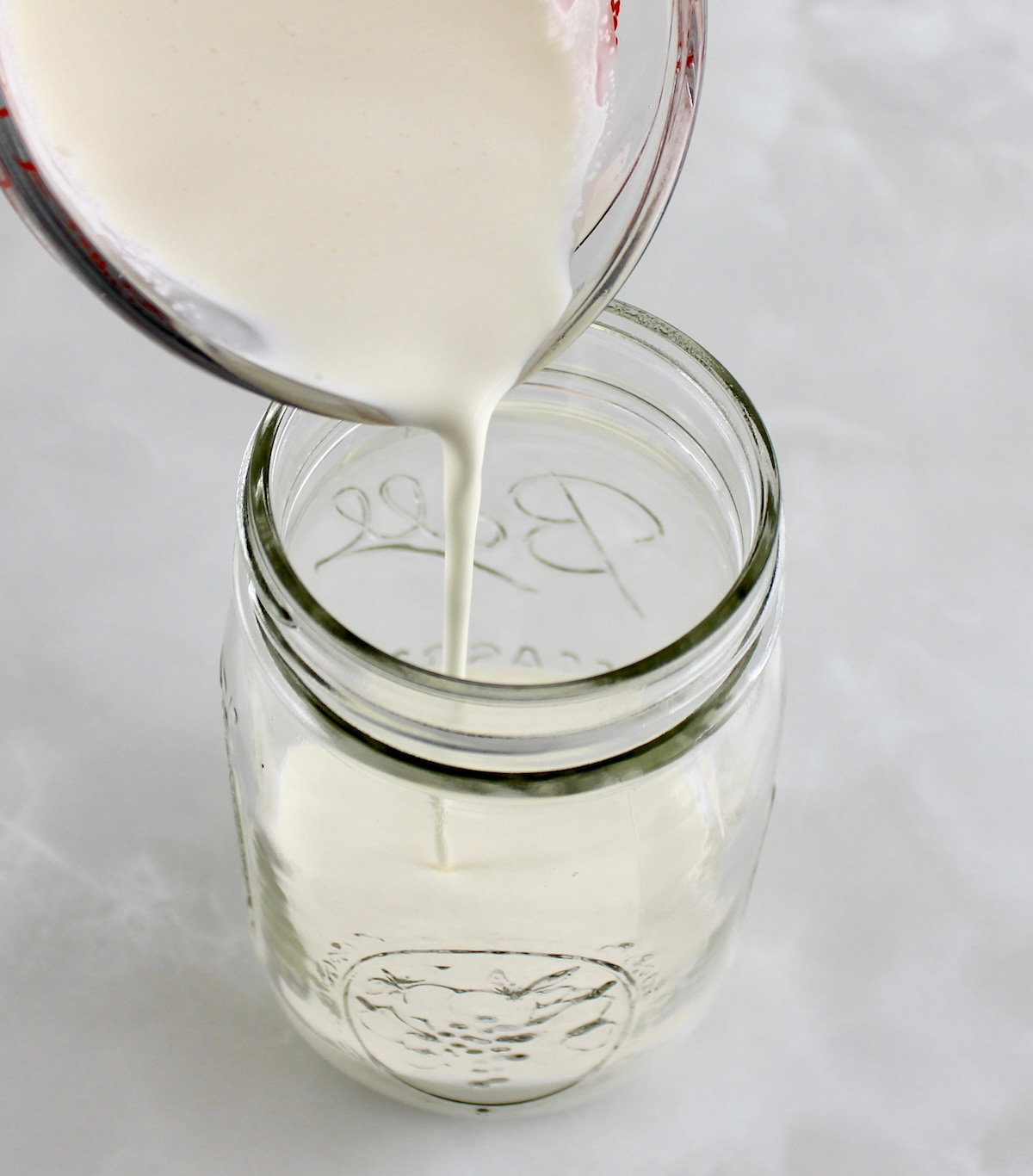 heavy cream being poured into open mason jar
