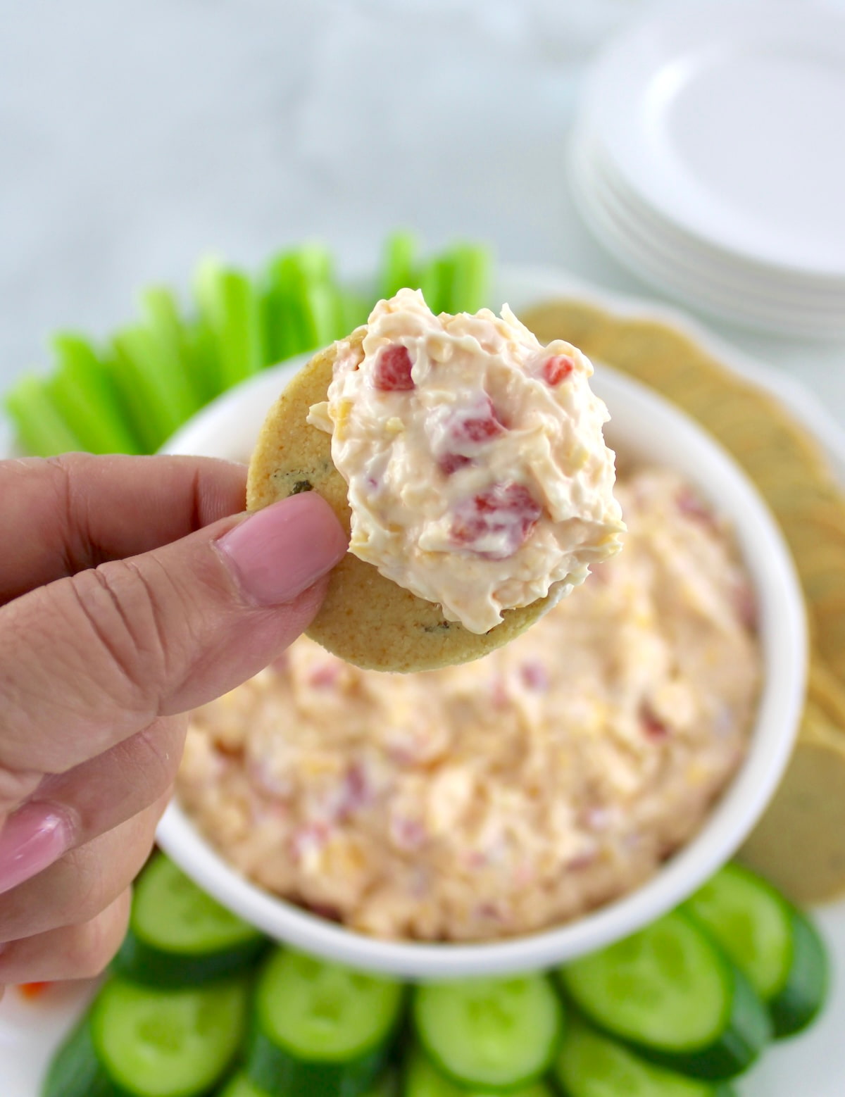 Pimento Cheese Spread held up on cracker with dip in background