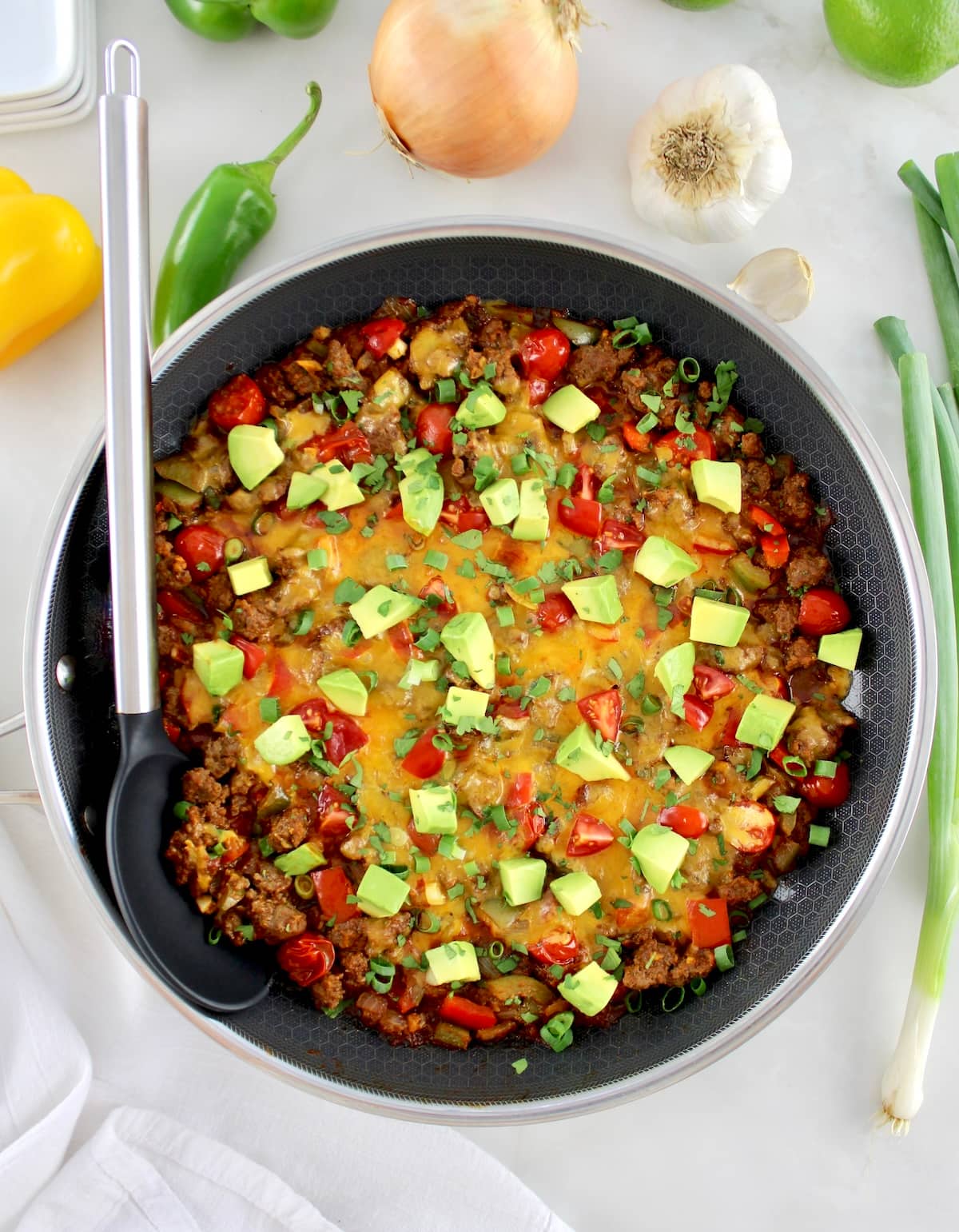 overhead view of Taco Skillet with diced avocado on top with serving spoon on side