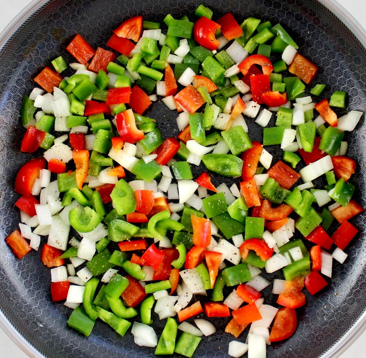 chopped green and red peppers and onions in skillet uncooked