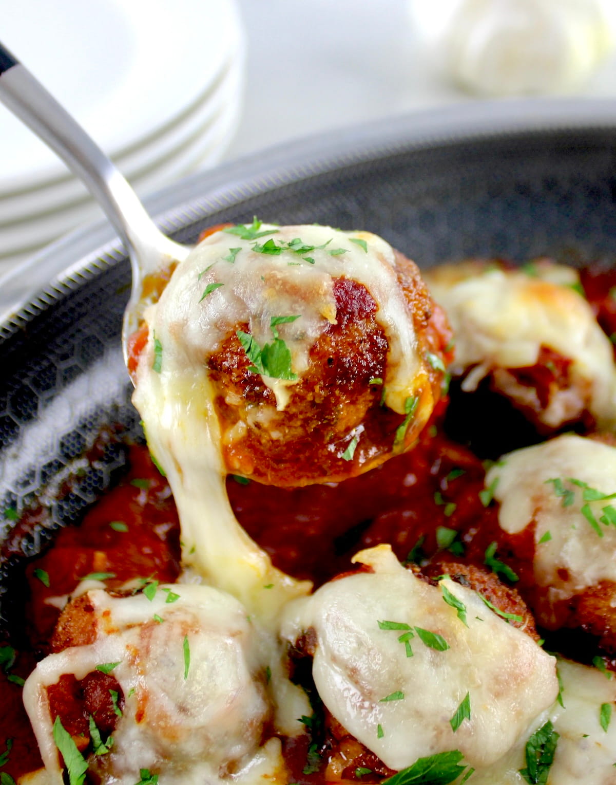 Chicken Parmesan Meatball being spooned out of skillet with cheese pull