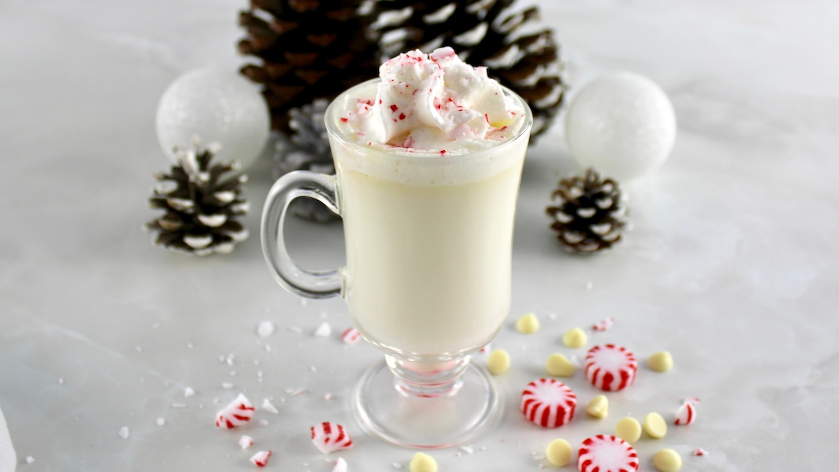 closeup side view of Peppermint White Hot Chocolate in glass with whip cream and crush mints on top