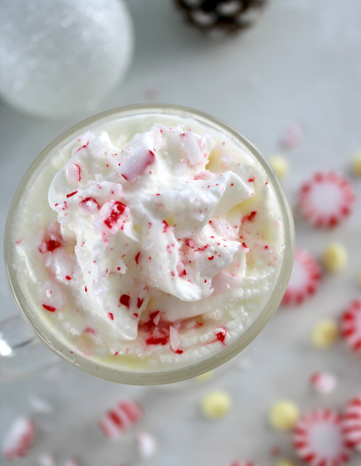 overhead view of Peppermint White Hot Chocolate in glass with whip cream and crush peppermints on top