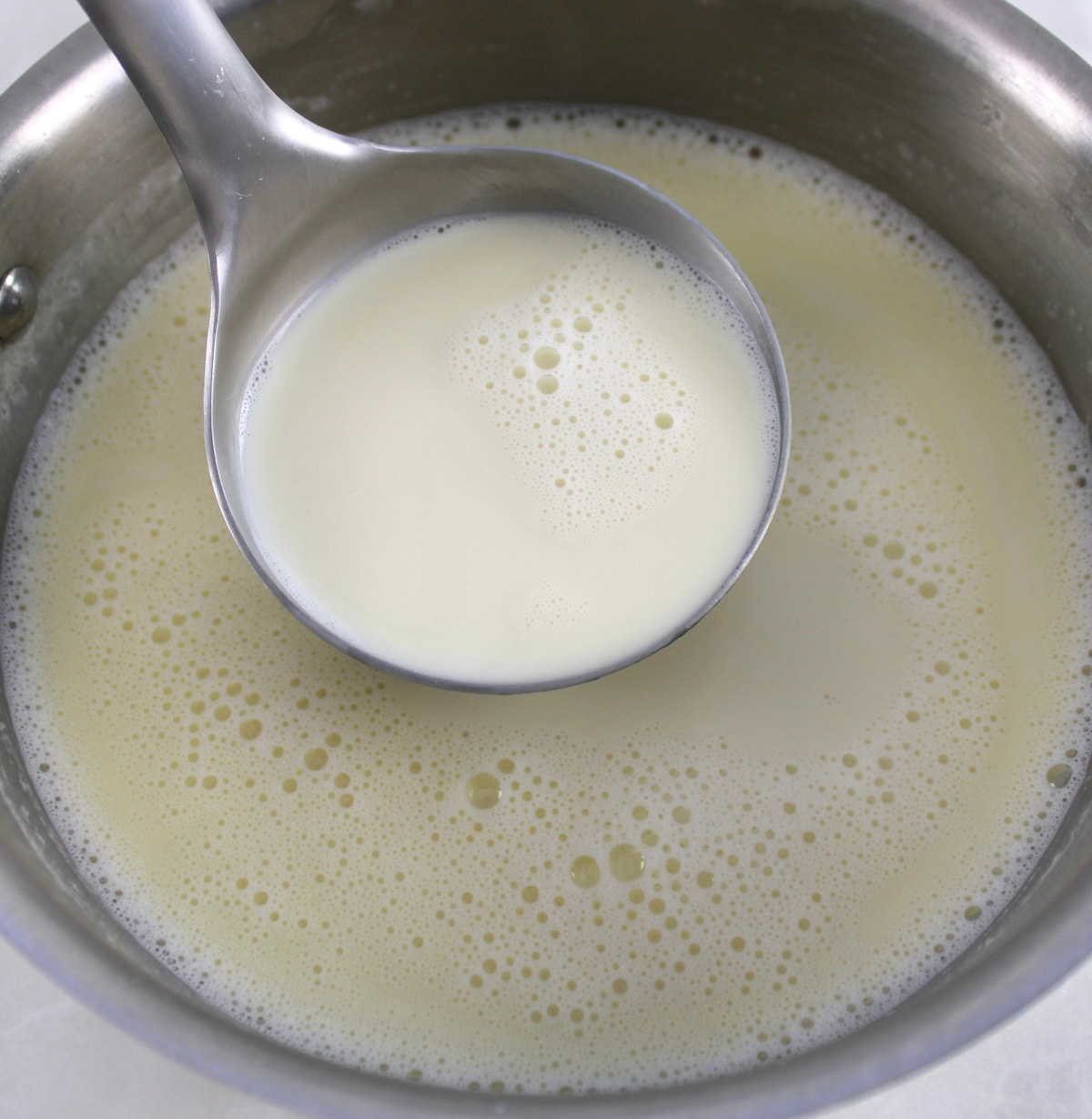 ladle scooping out Peppermint White Hot Chocolate of pot