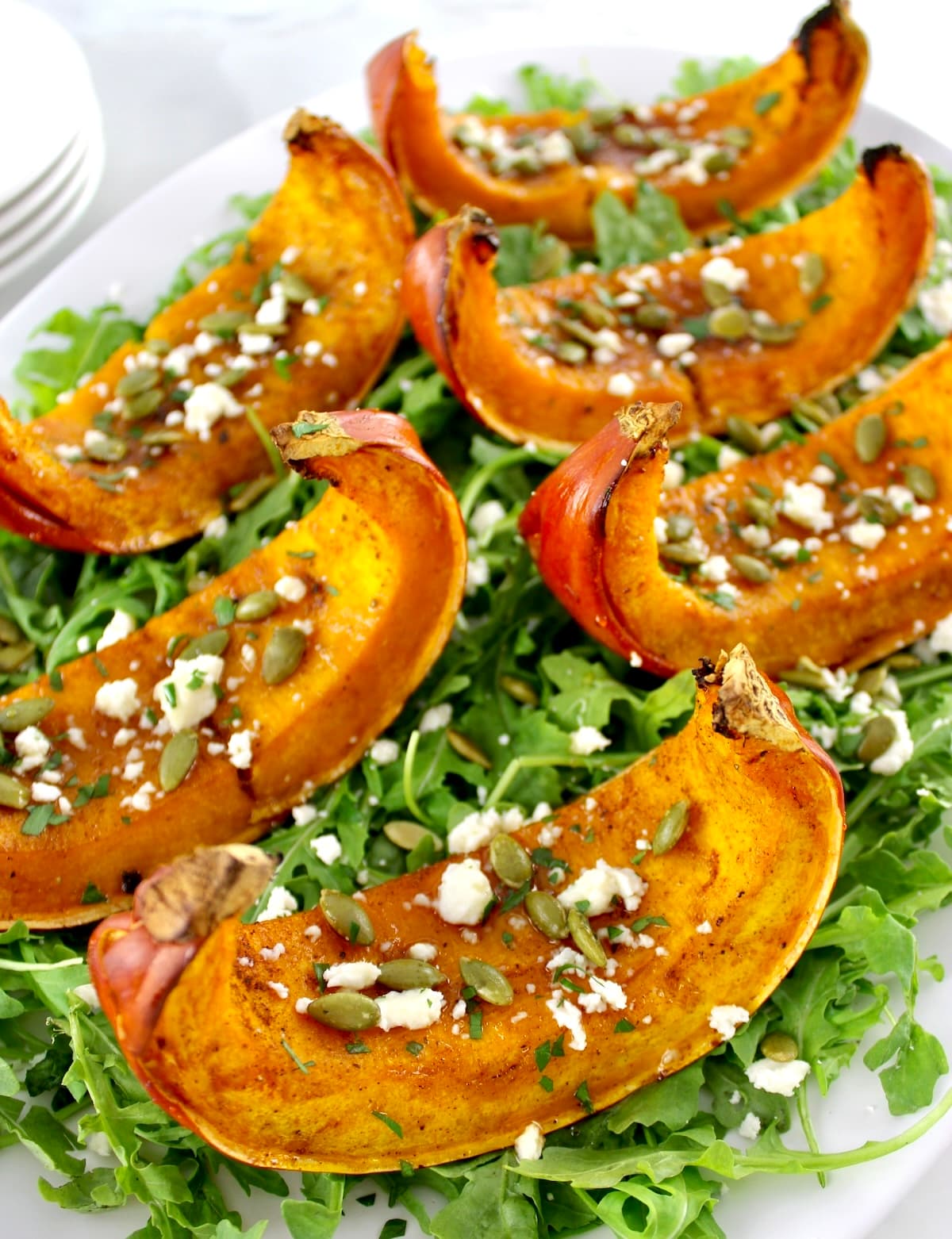 Roasted Pumpkin wedges on bed of arugula with pumpkin seeds and feta on top