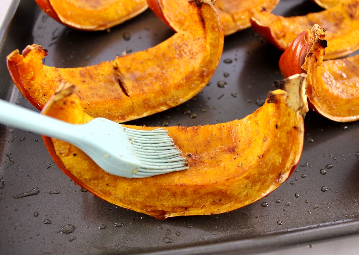 closeup of pumpkin wedge being brushed with maple syrup