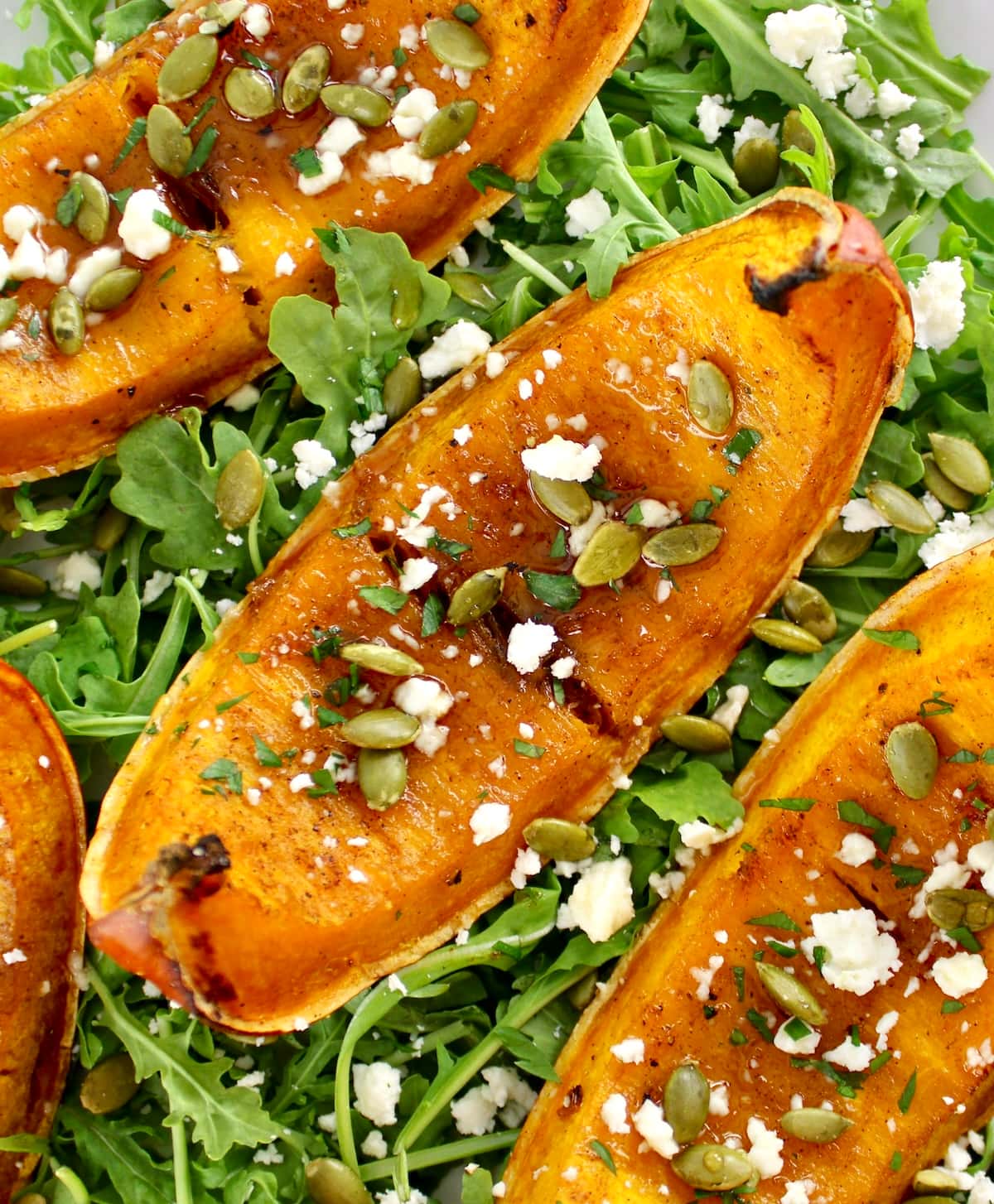closeup of Roasted Pumpkin on arugula on white platter