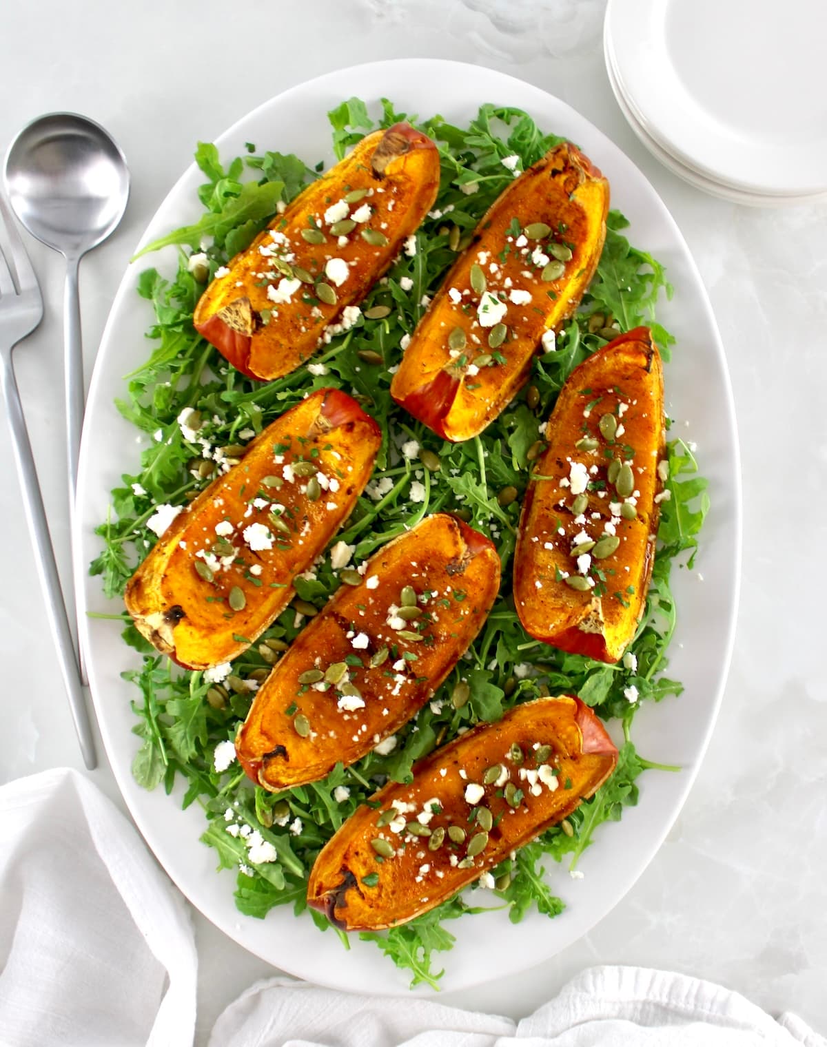 overhead view of Roasted Pumpkin on white oval platter with arugula